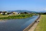 大きな川沿いの堤防を歩いている人達の写真